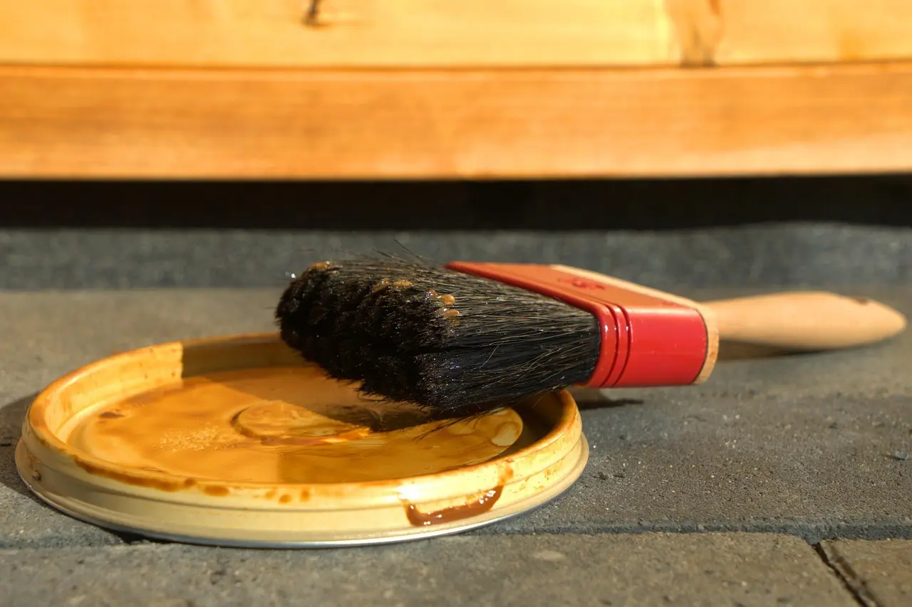Nærbillede af pensel med brun maling på et låg
